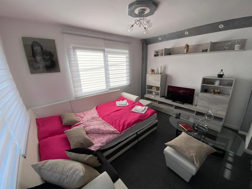 um quarto com uma cama grande e um cobertor rosa em Apartmani Lipa em Višegrad