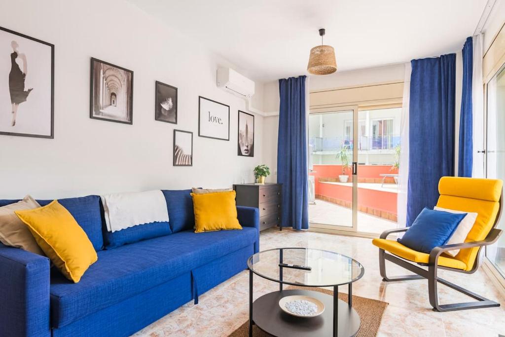 a living room with a blue couch and yellow chairs at Grand Apartament Lloret in Lloret de Mar