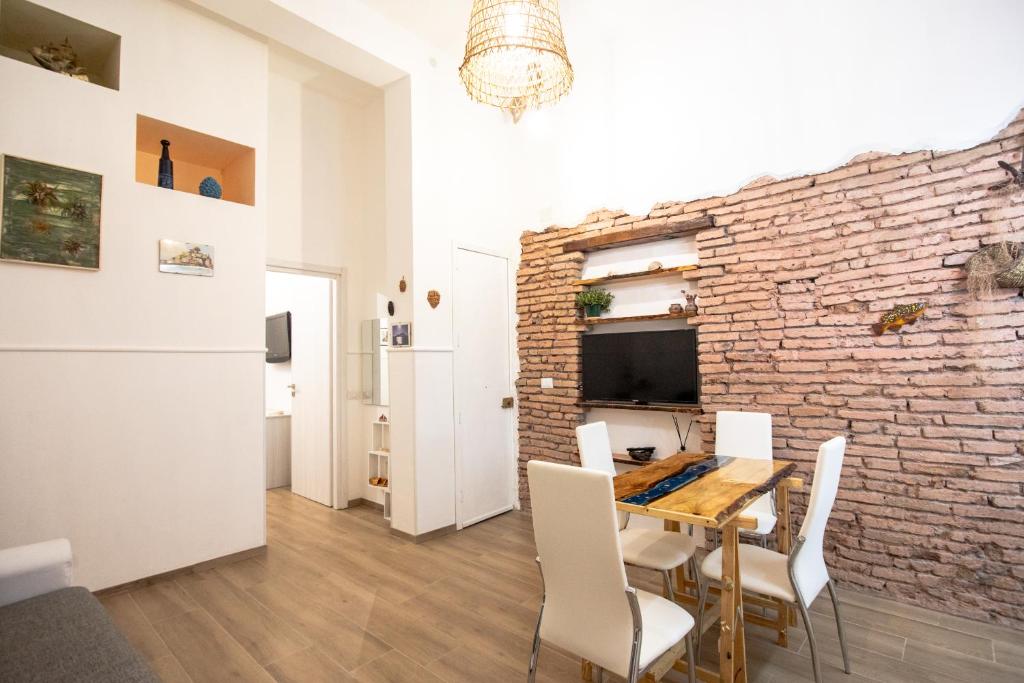 jadalnia z ceglaną ścianą oraz stołem i krzesłami w obiekcie casa vacanze Casa del Mare w mieście Aci Trezza
