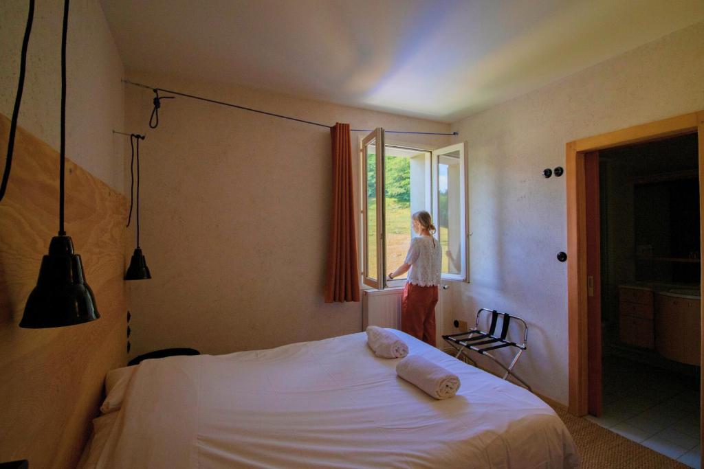 a woman looking out the window of a bedroom at Hostel Quartier Libre in Saint-Jean-en-Royans