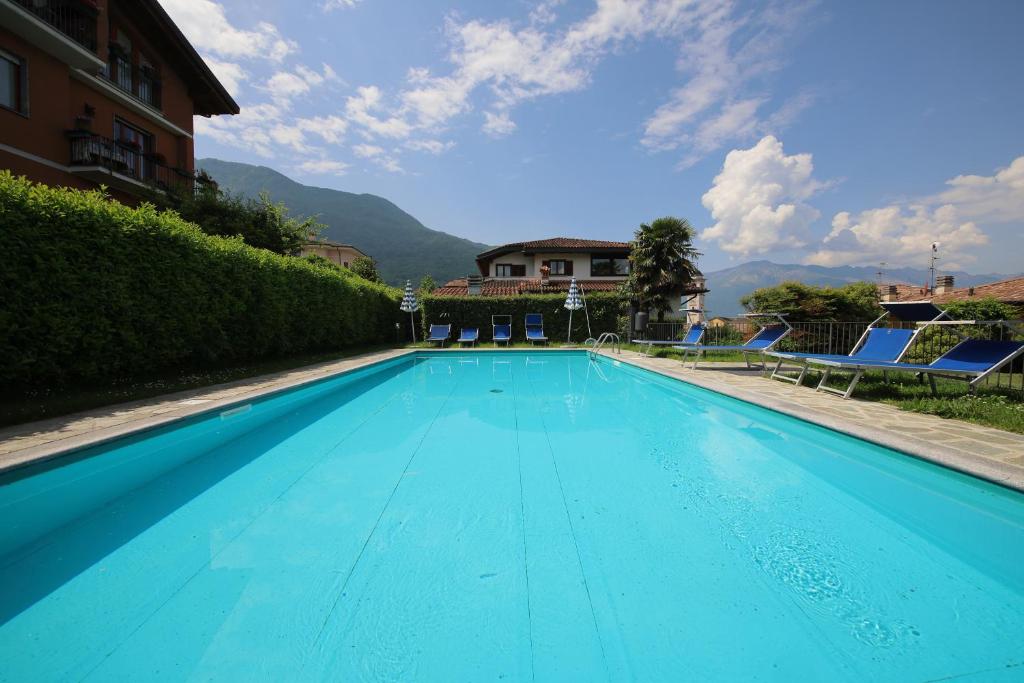 a blue swimming pool with chairs and a house at Villa Quattro Stagioni in Colico