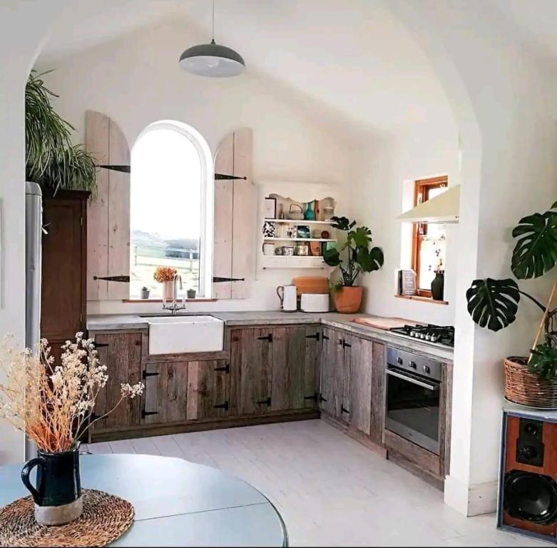 uma cozinha com armários de madeira, um lavatório e uma janela em The Carton Store Loft Apt em Cork