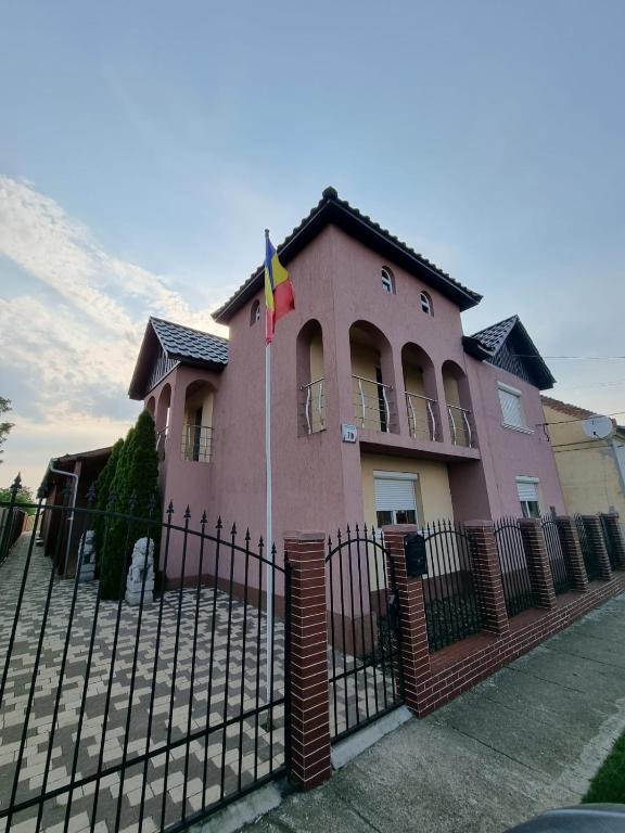 a pink house with a fence and a flag at Parnica Home 3 in Dudeştii Noi