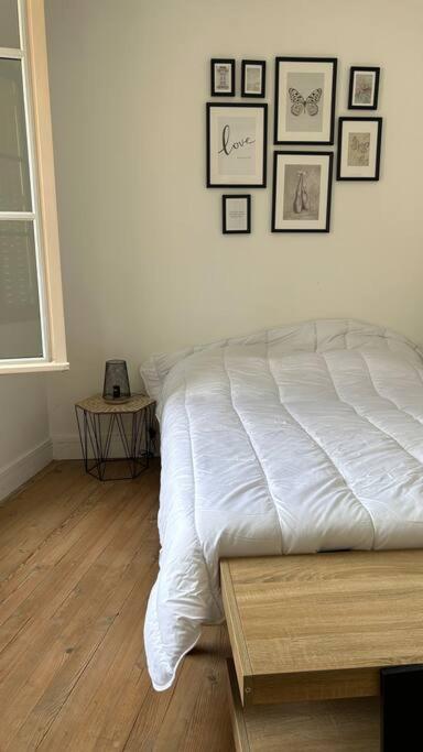 a bedroom with a white bed and pictures on the wall at Appartement cœur de ville in Châtillon-sur-Indre