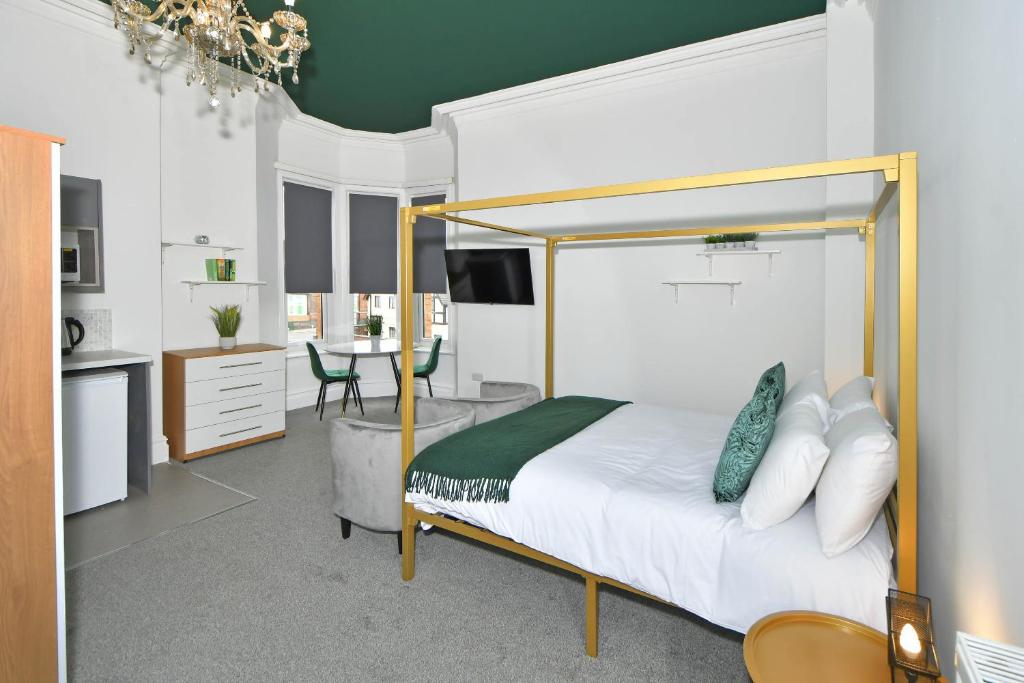 One Battison - Affordable Rooms, Suites & Studios in Stoke on Trent في ستوك أون ترينت: غرفة نوم مع سرير مظلة ومطبخ