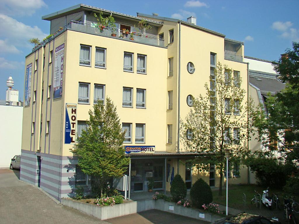 - un bâtiment jaune avec un balcon au-dessus dans l'établissement Senator Hotel, à Francfort-sur-le-Main