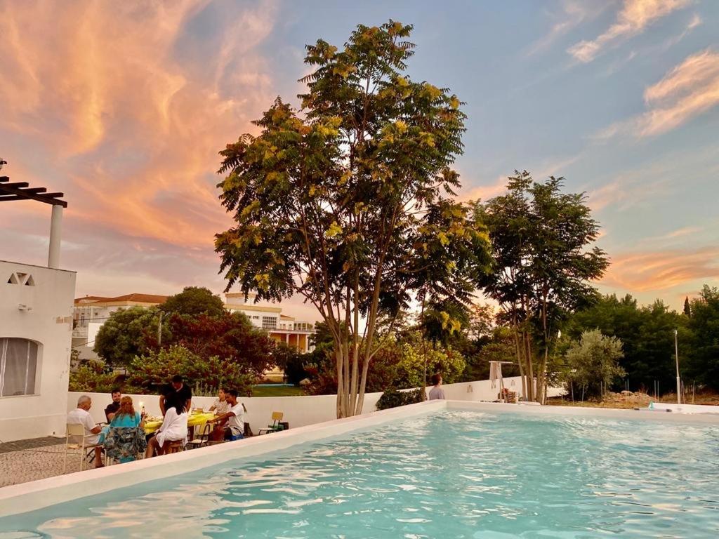 uma grande piscina com pessoas sentadas em cadeiras à sua volta em CASAS NAS TERMAS em Cabeço de Vide