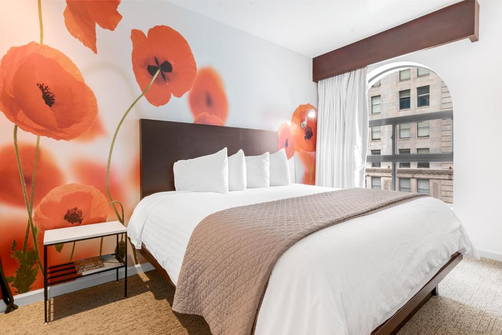 1 dormitorio con 1 cama con flores rojas en la pared en O Hotel by LuxUrban, en Los Ángeles