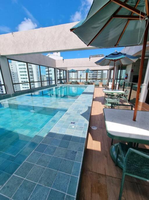 a swimming pool with an umbrella and tables and chairs at Flat em Boa Viagem 100% Equipado in Recife