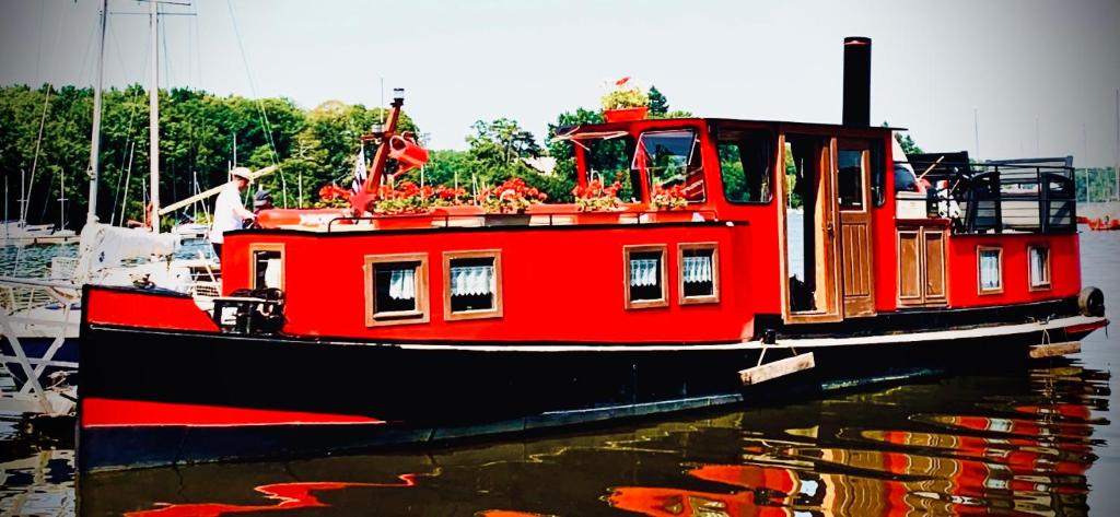 um barco vermelho está sentado na água em Magnifique péniche remorqueur à louer em Évran