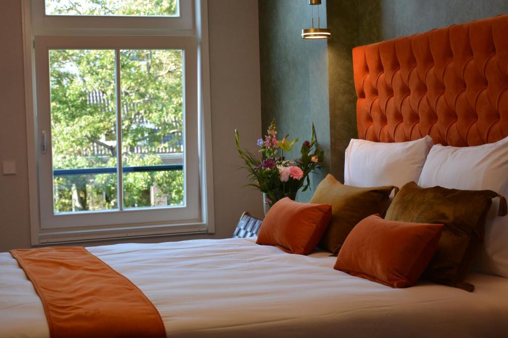a large bed with an orange headboard and a window at The IF Boutique hotel in Amsterdam