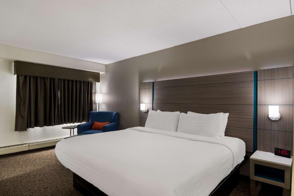 a bedroom with a large white bed and a blue chair at Best Western Bemidji in Bemidji