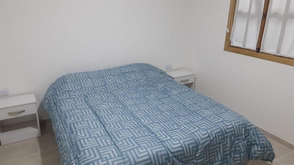 um quarto com uma cama com uma colcha azul e branca em Cabaña La Escondida em Trelew