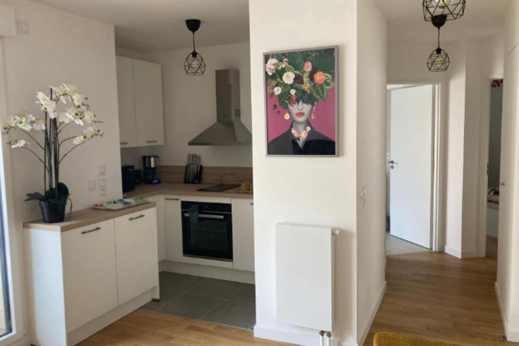 a kitchen with white cabinets and a painting on the wall at Very nice 40 m quiet in Suresnes with parking in Suresnes