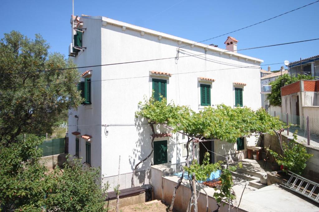 un edificio blanco con ventanas con contraventanas verdes en Apartments by the sea Unesic - Unije, Losinj - 8044 en Unije