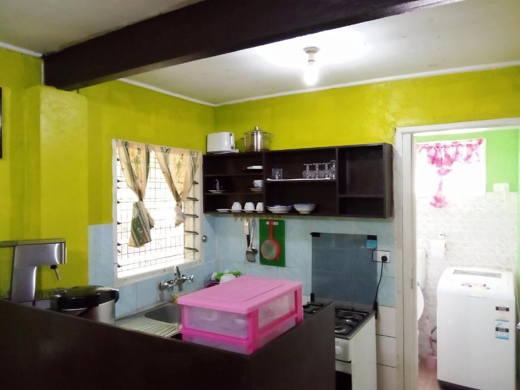 cocina con paredes amarillas y caja rosa en Island Home, en Honiara