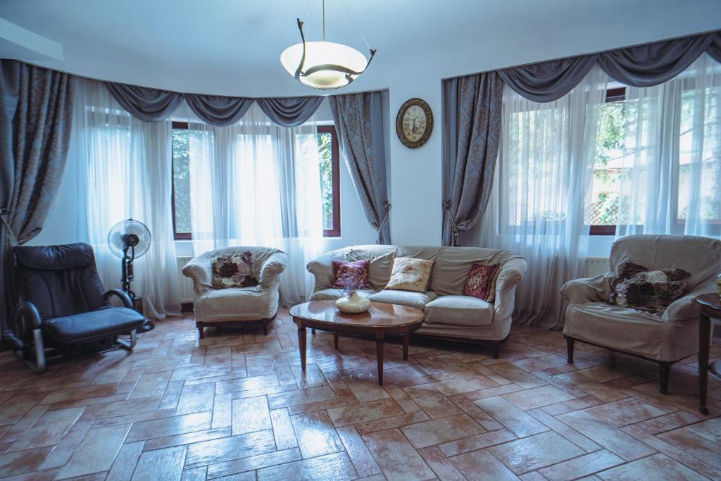 - un salon avec un canapé, des chaises et une table dans l'établissement Luxuria Central Villa Bucharest, à Bucarest