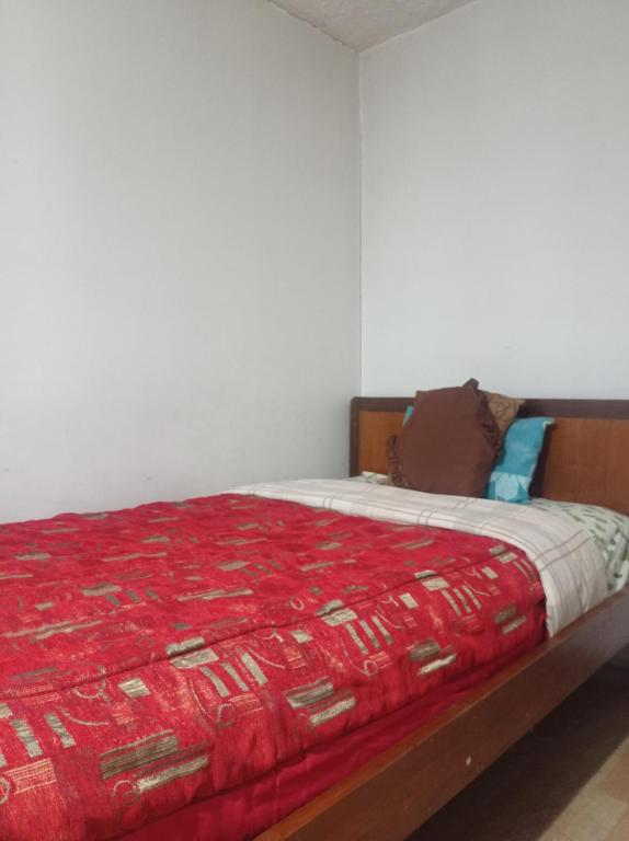 1 dormitorio con 1 cama con manta roja en ESCOCIE-PLAZA G, en Quito