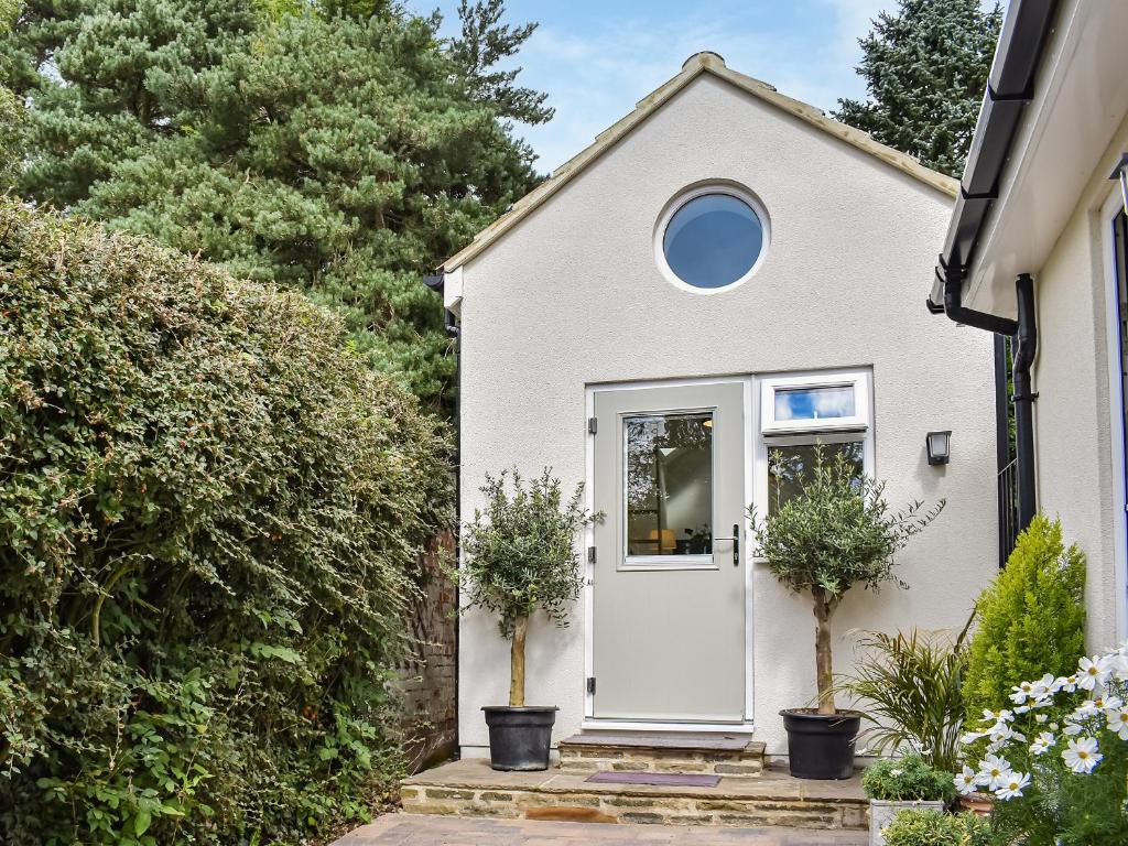 a white house with a white door and two potted plants at Green Acres in Nidd