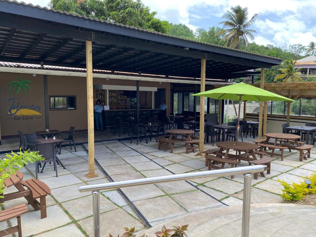 a patio with tables and chairs and a green umbrella at Myah's Hotel in Brighton Village