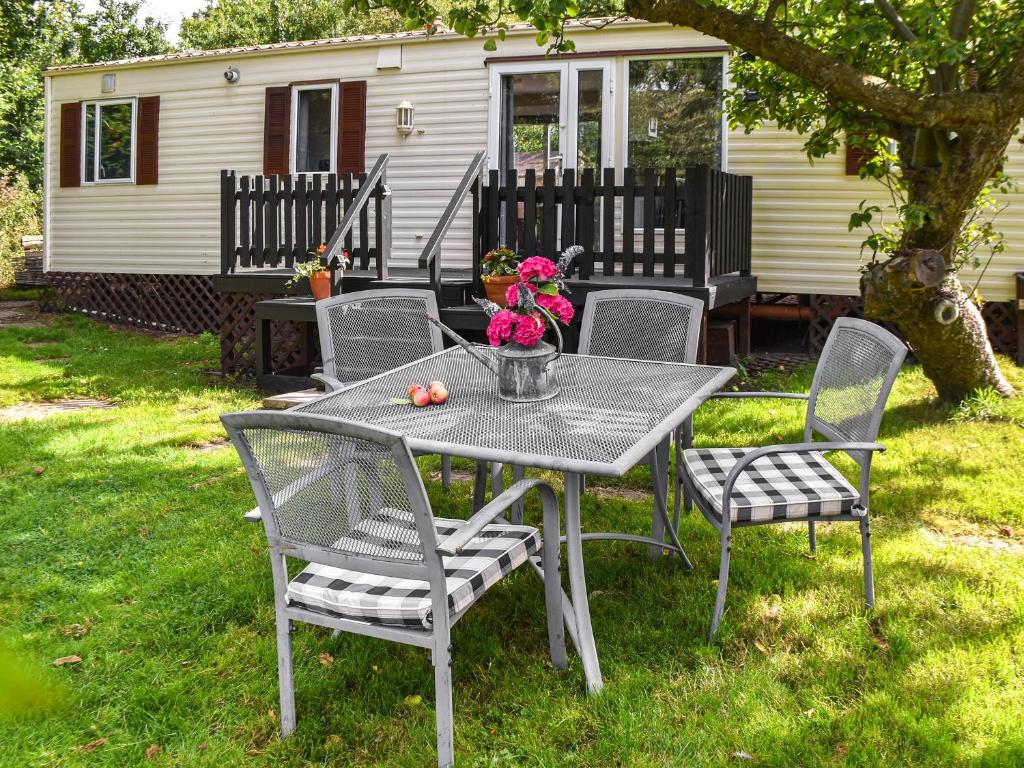 a table and chairs with flowers on a yard at Meadow View Van - Uk44667 in Neatishead