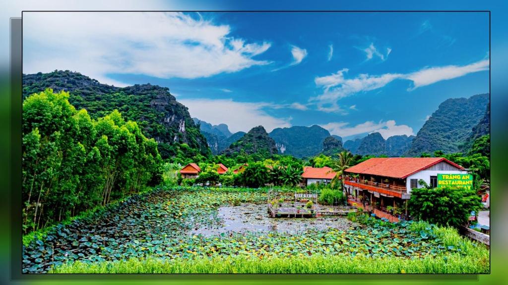 a group of houses on a river with mountains in the background at Trang An Homestay in Ninh Binh