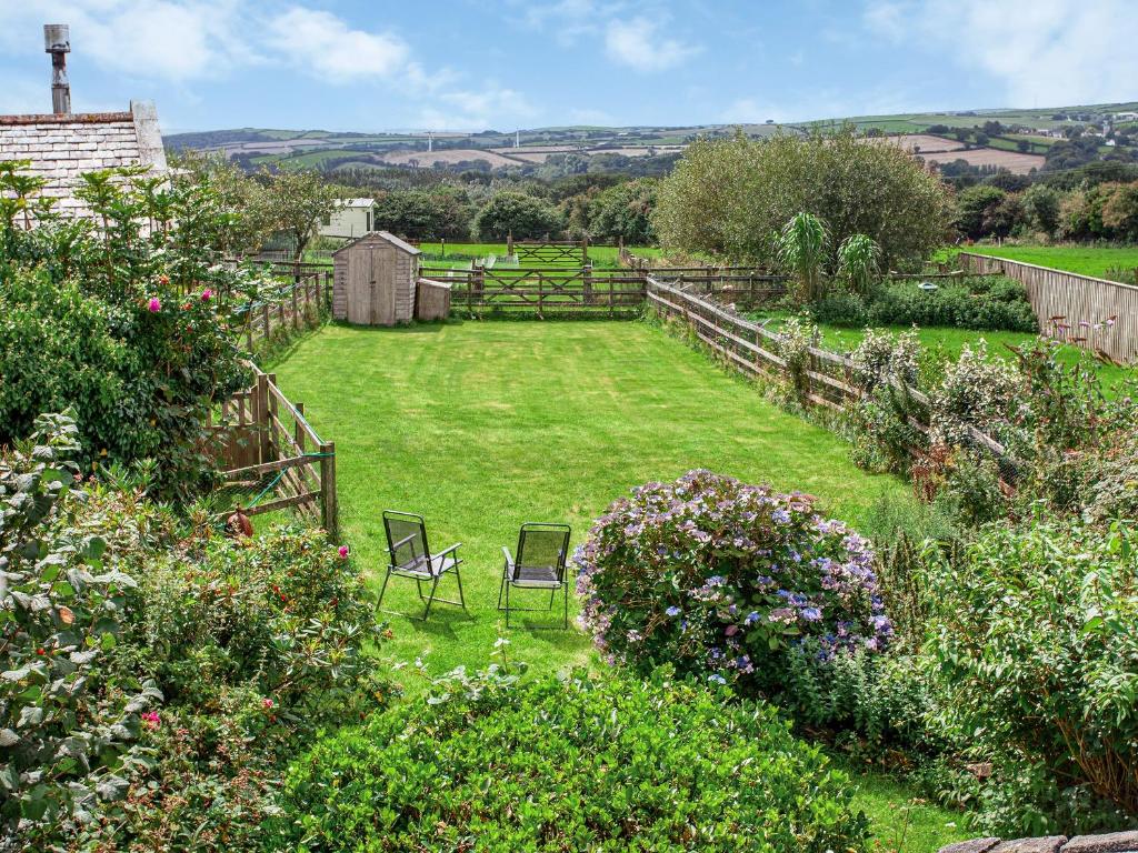 a garden with two chairs in the grass at Mayrose Cottage in Lanteglos