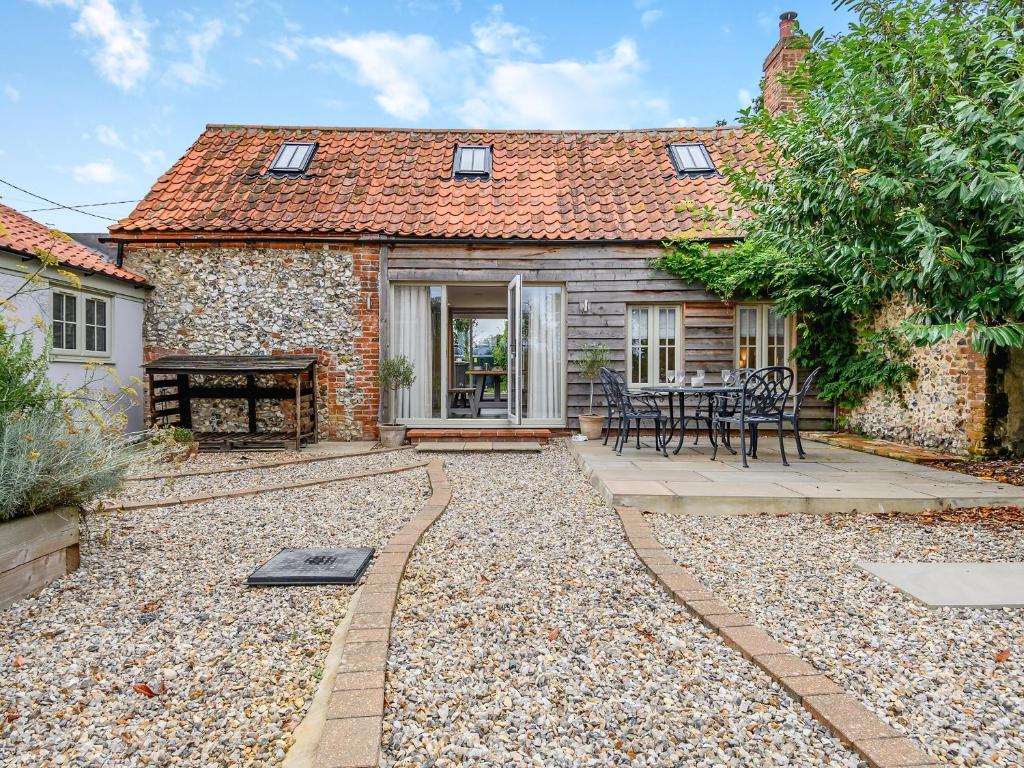 a cottage with a patio and a table and chairs at The Granary in Great Fransham