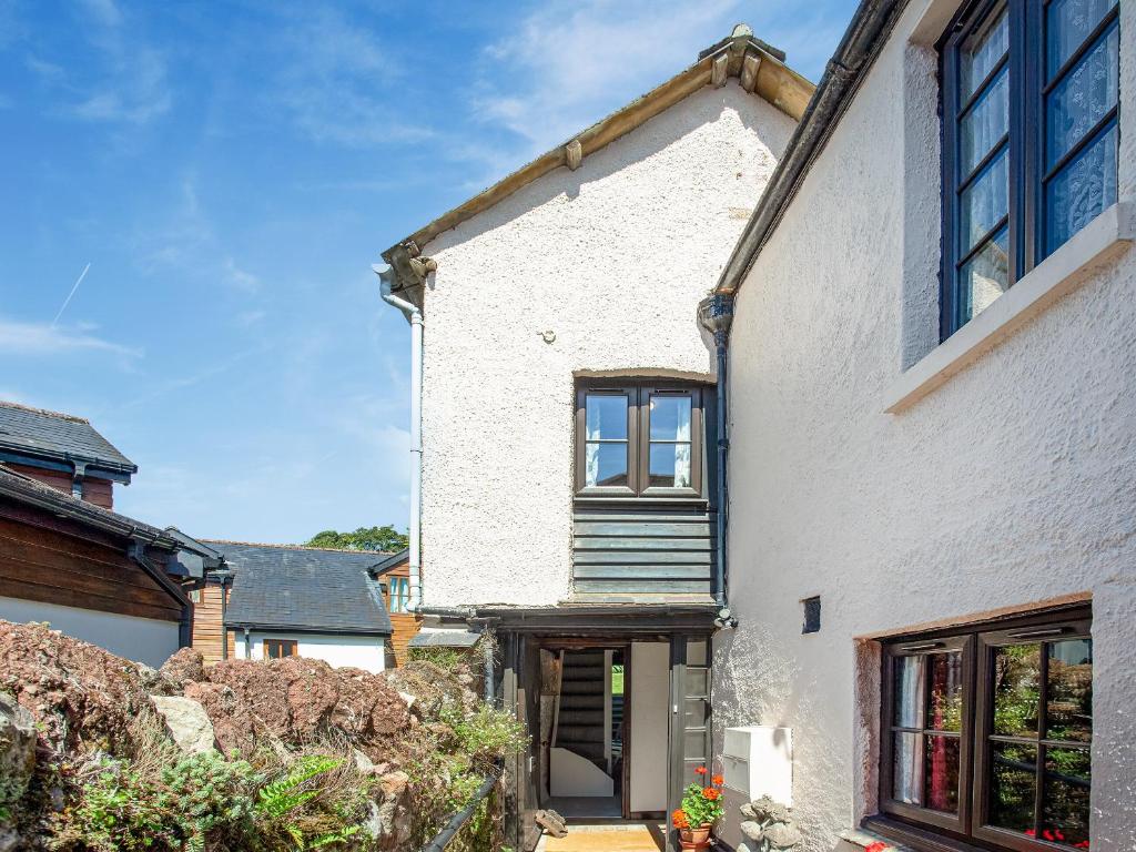 a white brick house with a porch and a window at The Granary in Stokeinteignhead