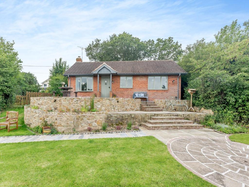 a brick house with a stone wall and a yard at High Bank in Pontesbury