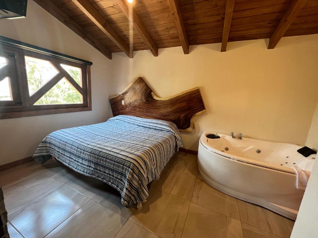 een slaapkamer met een bed en een bad bij Cabaña Lunamiel 3 in Mazamitla