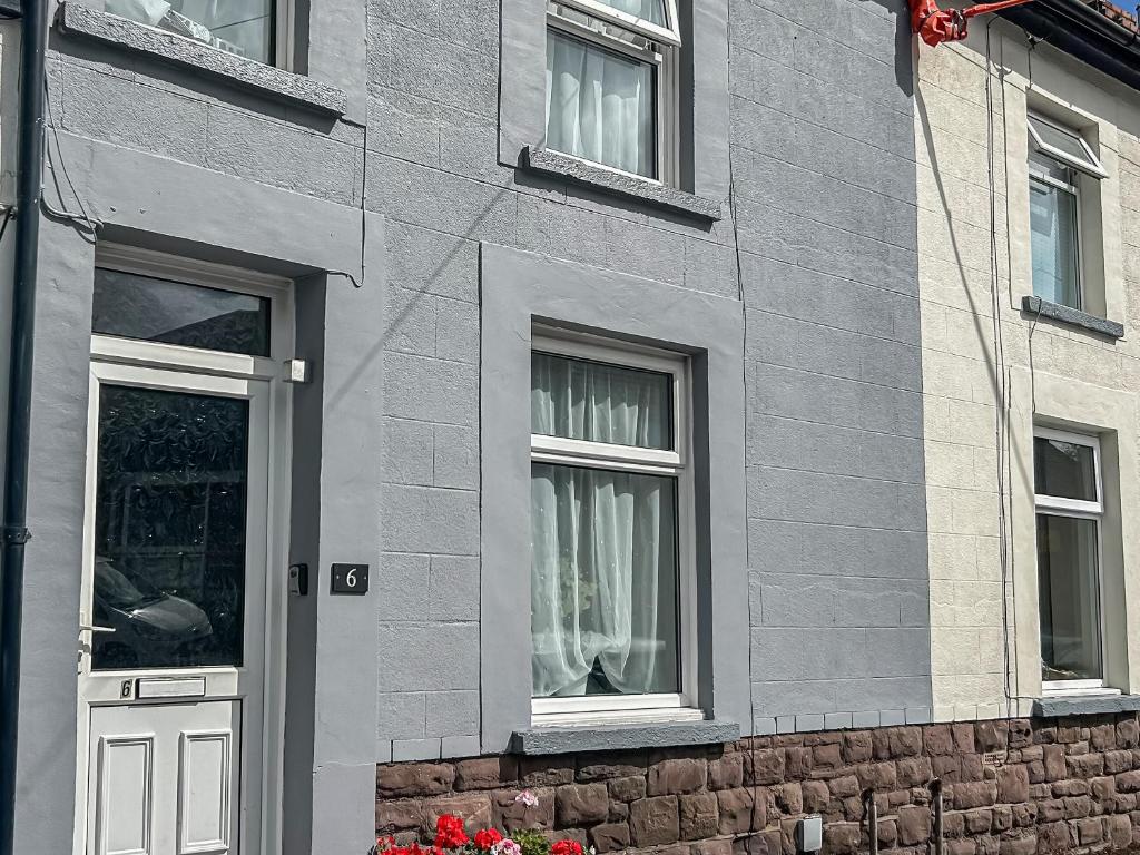 a gray brick building with a door and two windows at Rhonas Cottage in Abergavenny