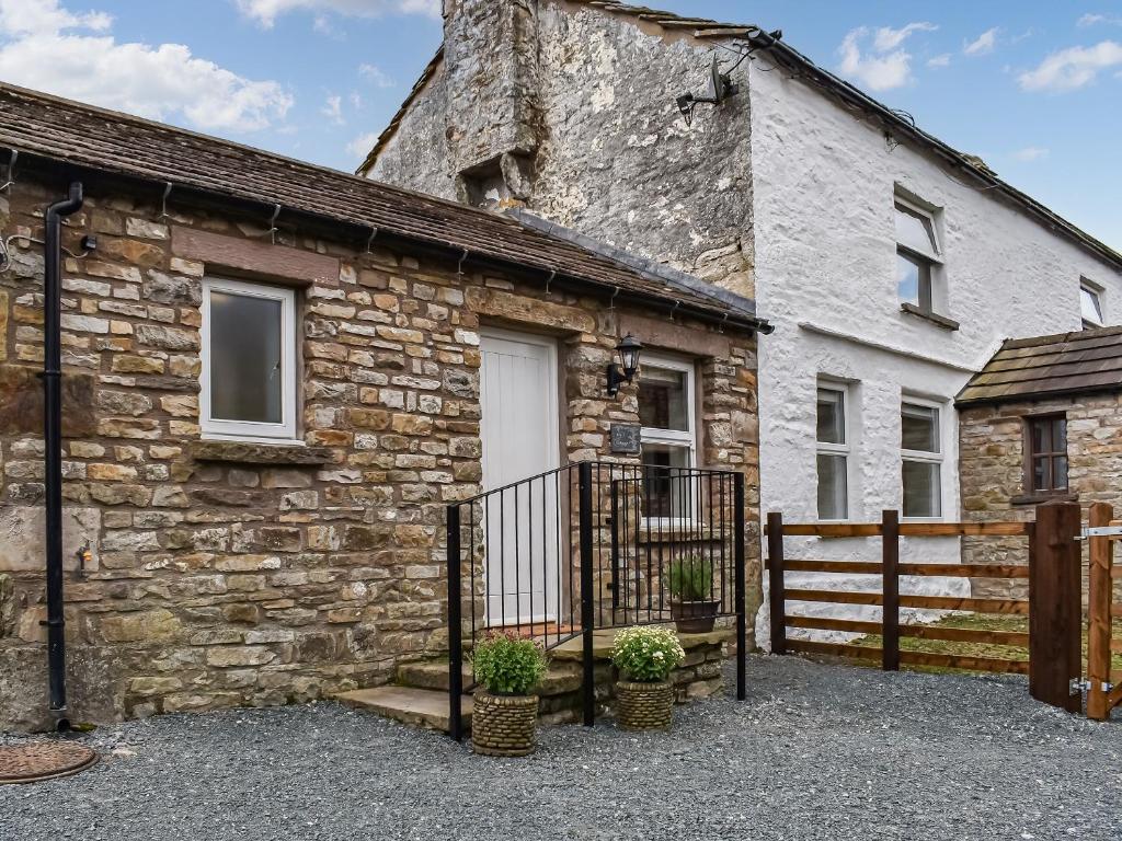 una casa de piedra con una puerta y una valla en Ivy Cottage en Dent