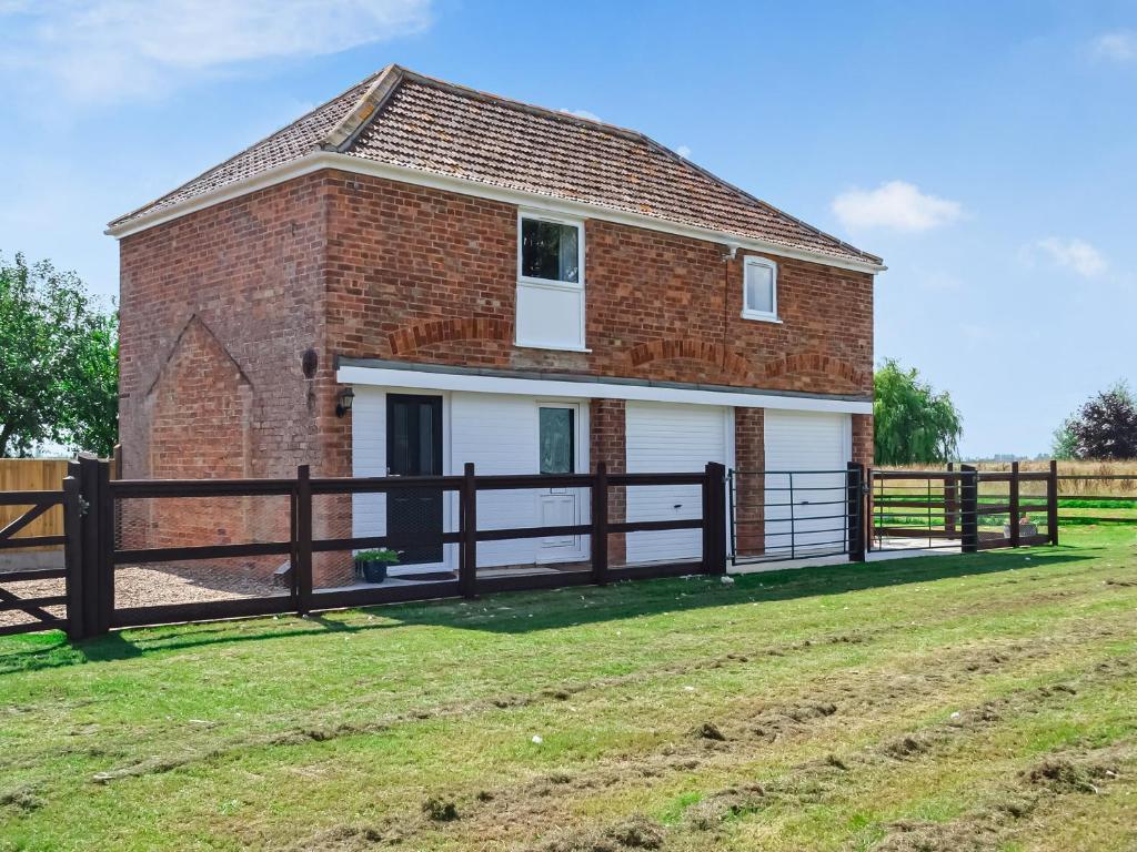 a brick barn with a fence in front of it at The Coach House in New Bolingbroke