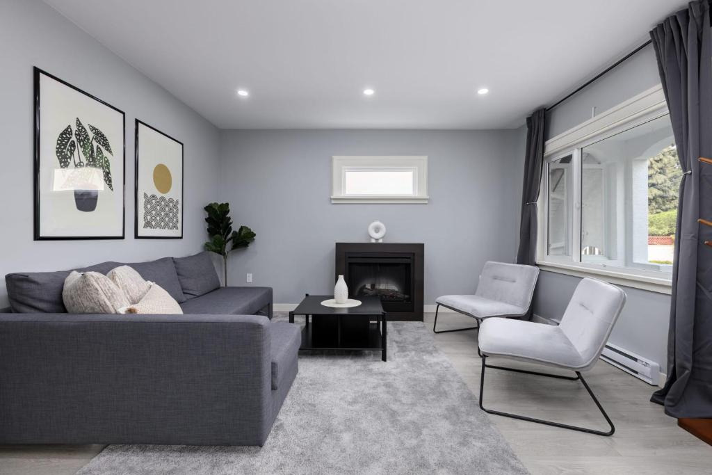 uma sala de estar com um sofá cinzento e uma lareira em Spacious 4 BR House in Park Drive em Vancouver