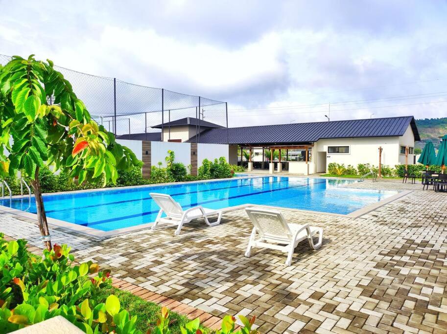 a swimming pool with two chairs in front of a house at NUEVA Hermosa casa vía Samborondón Coliving Ecuador in Guayaquil
