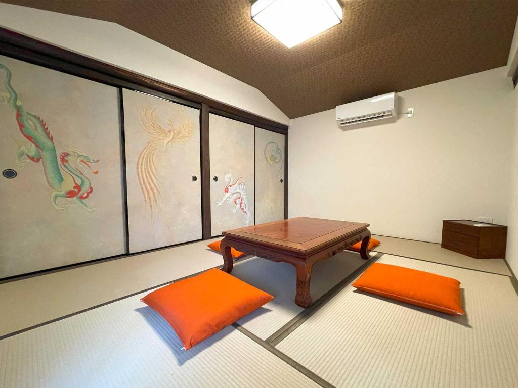 una habitación con una mesa y dos alfombras de color naranja en Asuka no yado-明日香の宿-, en Asuka