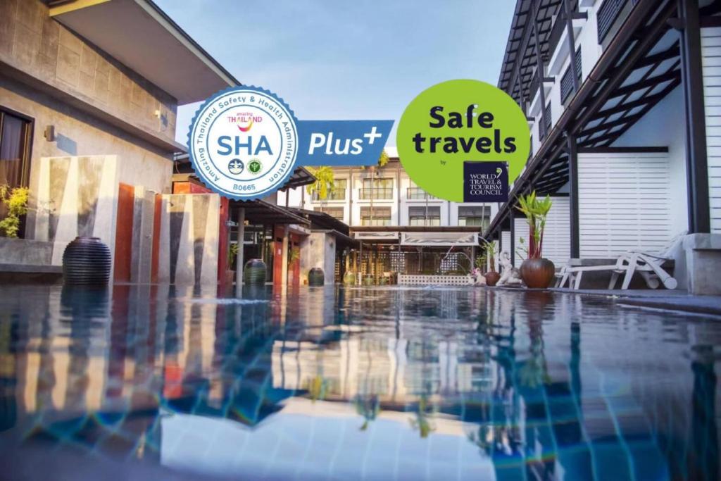 ein Schwimmbad mit Schildern an der Seite eines Gebäudes in der Unterkunft Phuketa - SHA Extra Plus in Phuket