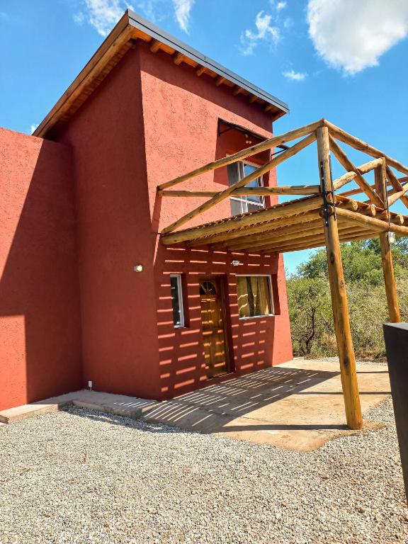 a large red building with a wooden structure at Cabaña La Yumba in Capilla del Monte