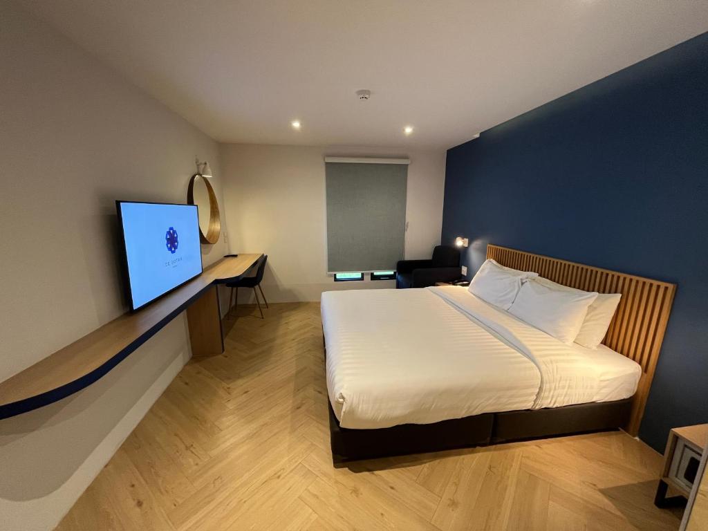 a hotel room with a bed and a flat screen tv at De Botan Bangna in Bangkok