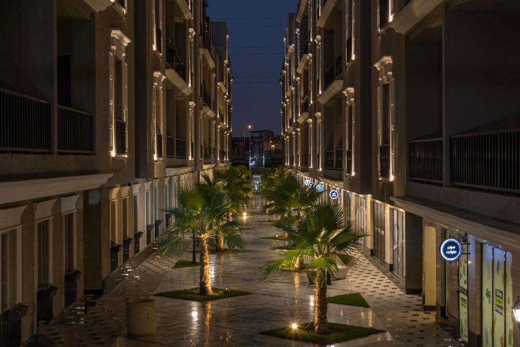 a hallway with palm trees in a building at night at luxury 3BR Condo Near the Boulevard in Riyadh
