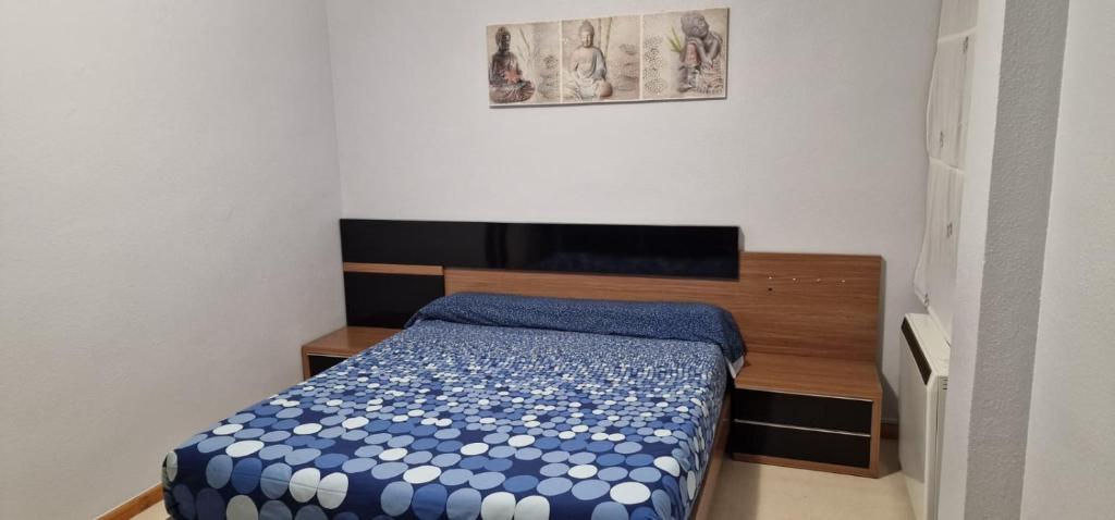 a small bedroom with a bed with a blue comforter at PISO CANAL in Valdepeñas