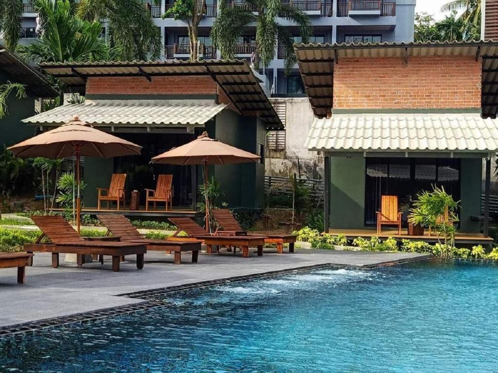 a pool with benches and umbrellas next to a building at Eco Inn Cottage Krabi at Aonang in Ao Nang Beach