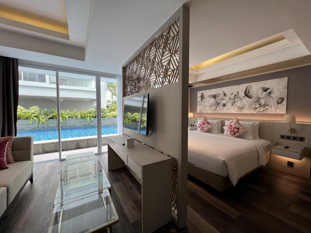 a bedroom with a bed and a tv and a couch at Arshika Bali Sunset Road in Kuta