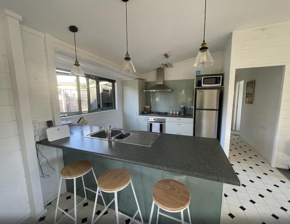 a kitchen with a counter with two stools and a sink at Kapanga Escape in Coromandel Town