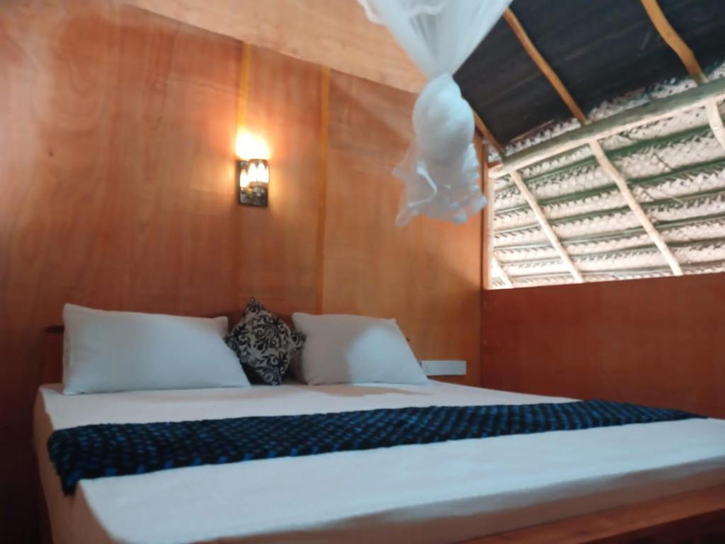 a bedroom with a white bed with a window at Pidurangala View Treehouse in Sigiriya