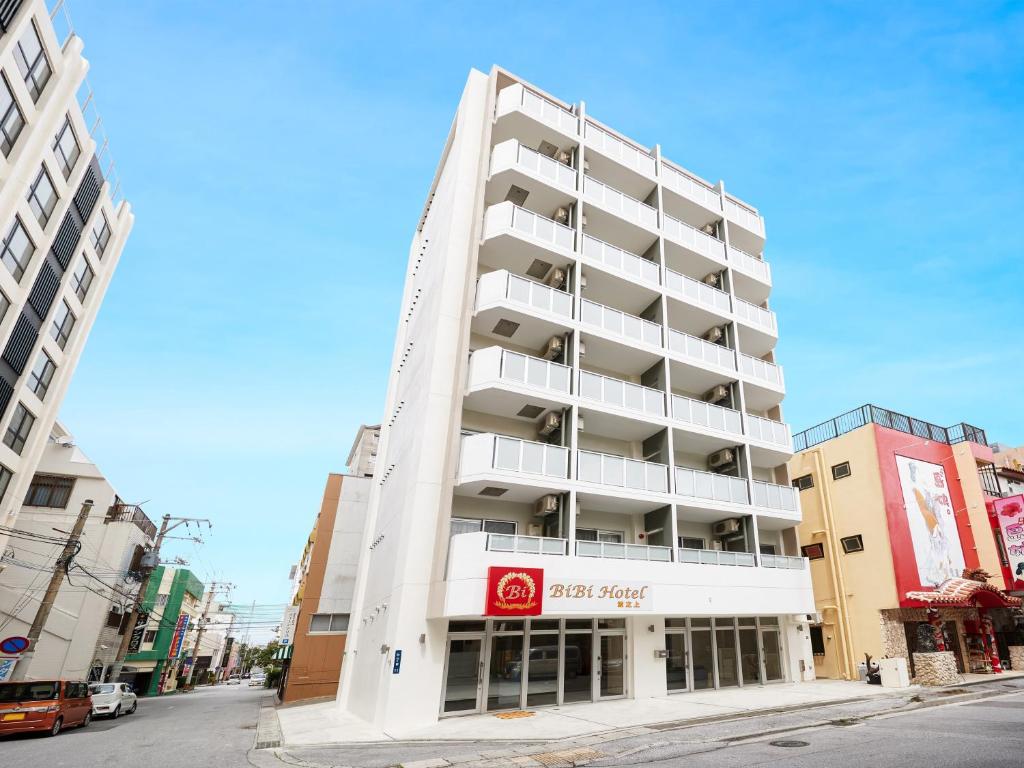 un edificio blanco alto en una calle de la ciudad en BiBi Hotel 波之上 en Naha