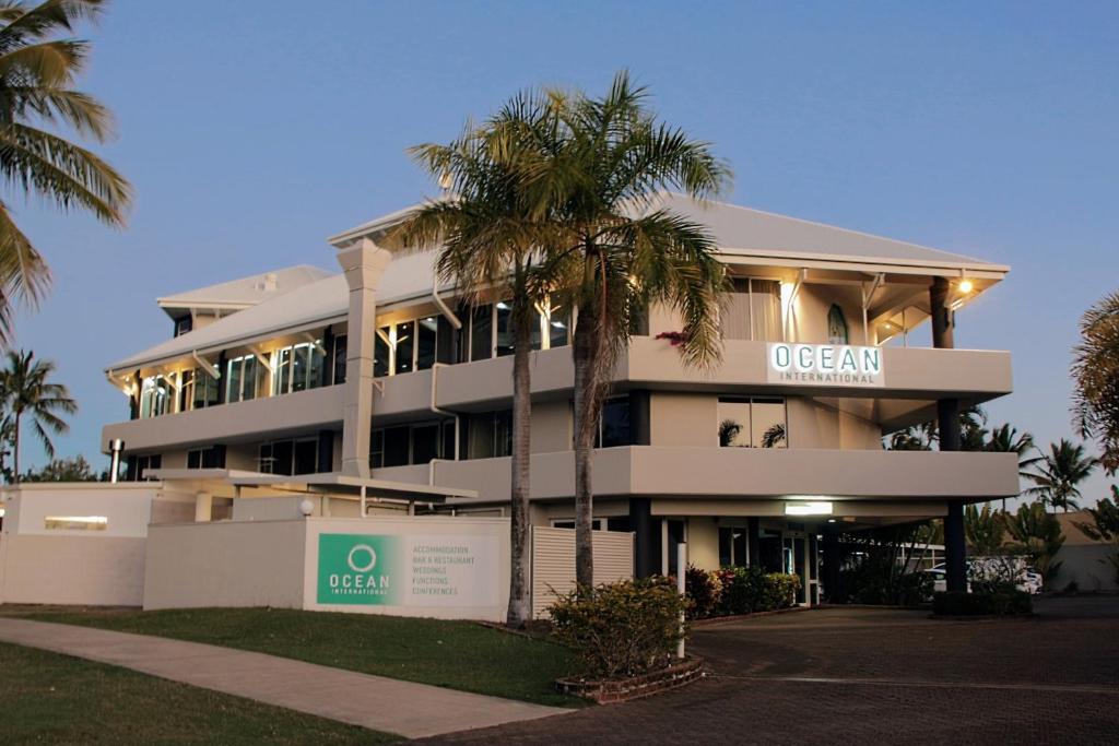 a building with a palm tree in front of it at Ocean International Hotel in Mackay