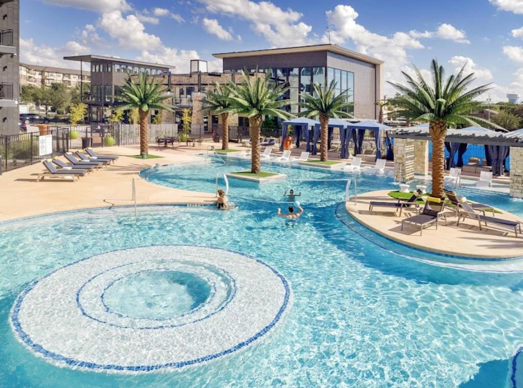 a large swimming pool with palm trees and a building at Cozy Retreat-Free Reserved Parking-Pool in Addison