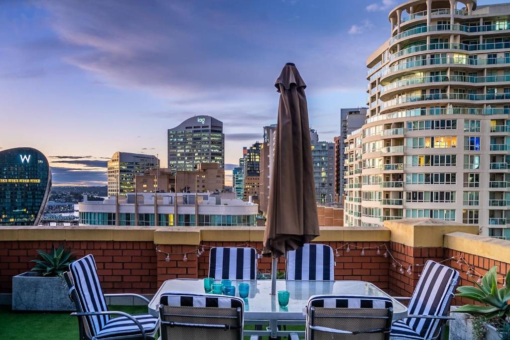 une table avec des chaises et un parasol sur un toit dans l'établissement Urban Sky Terrace in the Vibrant Heart of Sydney, à Sydney